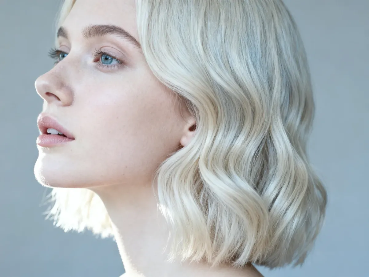 Stylowa fryzura typu „cool girl bob” z delikatnymi falami na jasnych włosach w profesjonalnym ujęciu.